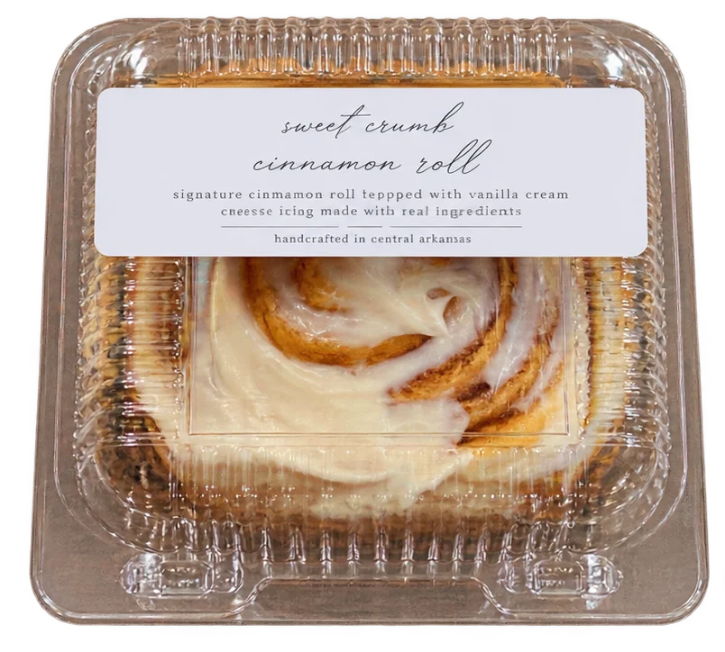 Sweet Crumb cinnamon roll with icing in a clear bakery clamshell